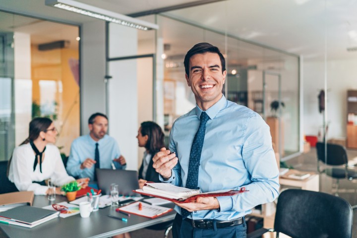 marketing consultant smiling while holding documents in a team discussion
